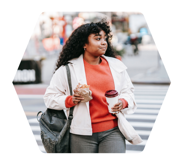Woman eating fast-food and drinking coffee wwhile walking